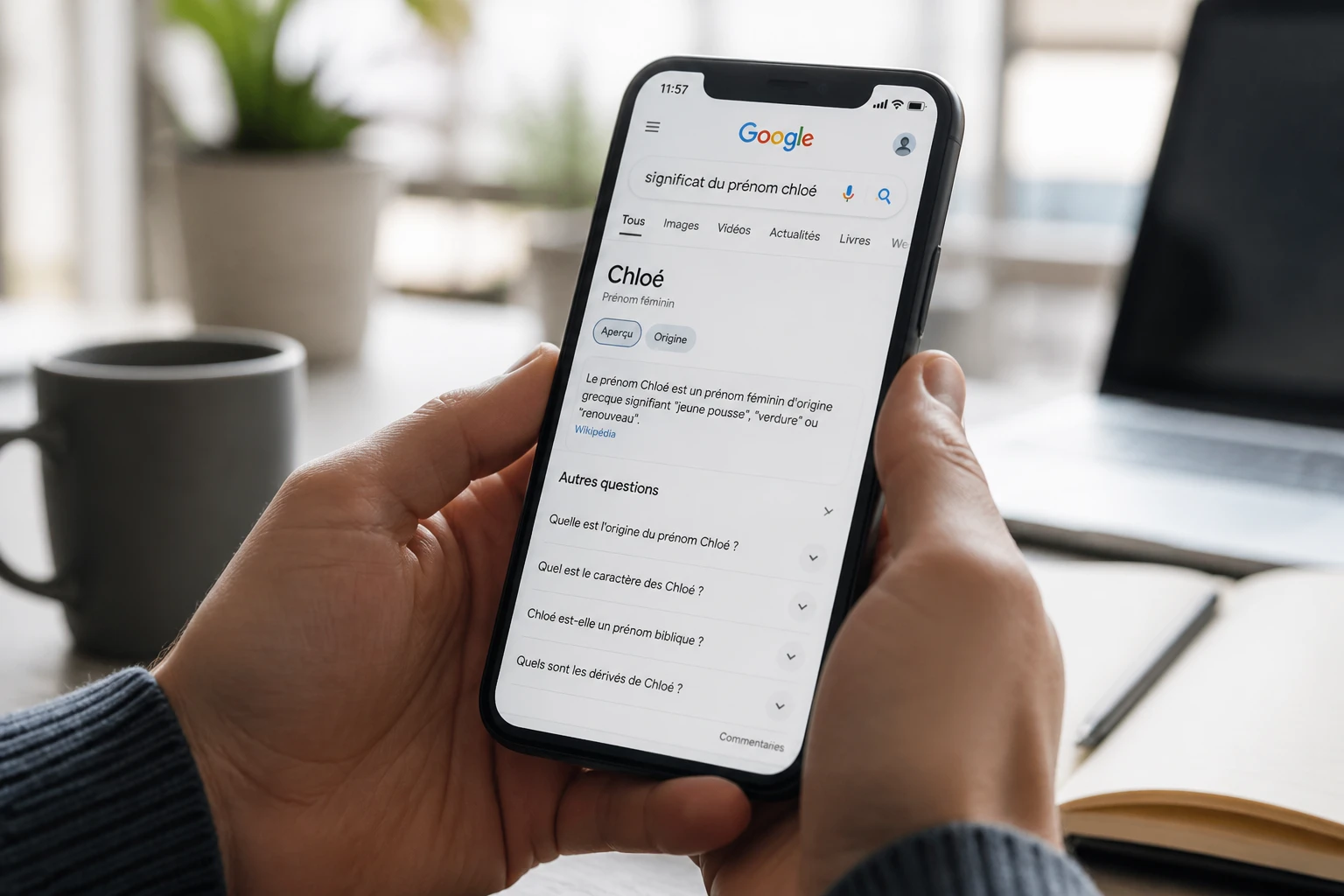 Smartphone affichant des résultats de recherche Google pour un nom propre français sur fond de bureau lumineux