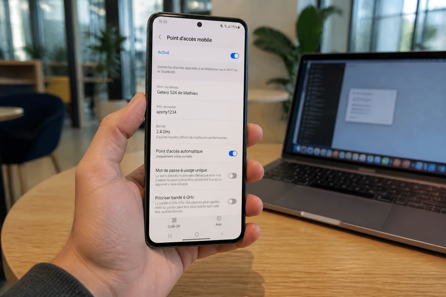 Smartphone Samsung affichant les réglages du point d'accès mobile à côté d'un ordinateur portable